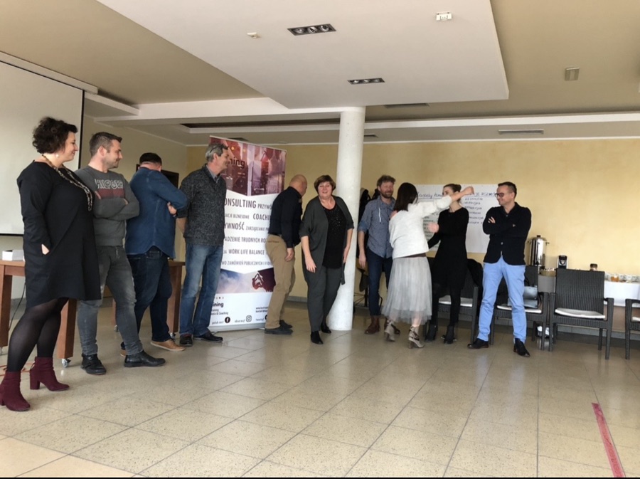 Uczestnicy szkolenia podczas ćwiczenia grupowego obok roll-upu Key Training